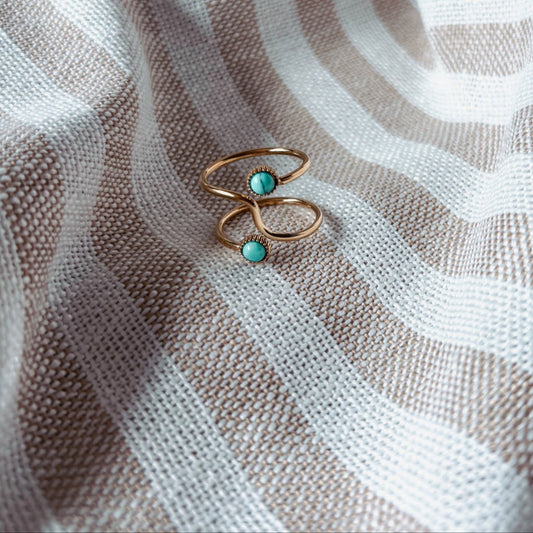 Gold ring with turquoise stones on a textured fabric background